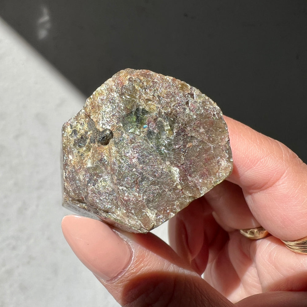 Hand holding an australian apatite against a neutral background