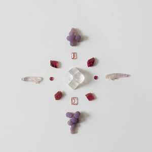 Crystal grid of various crystals and gemstones on a light gray background - compassion and change grid