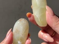 
                
                    Load and play video in Gallery viewer, Two hands holding a pair of tumbled  Australian Prehnite meditation harmonisers against a neutral background
                
            